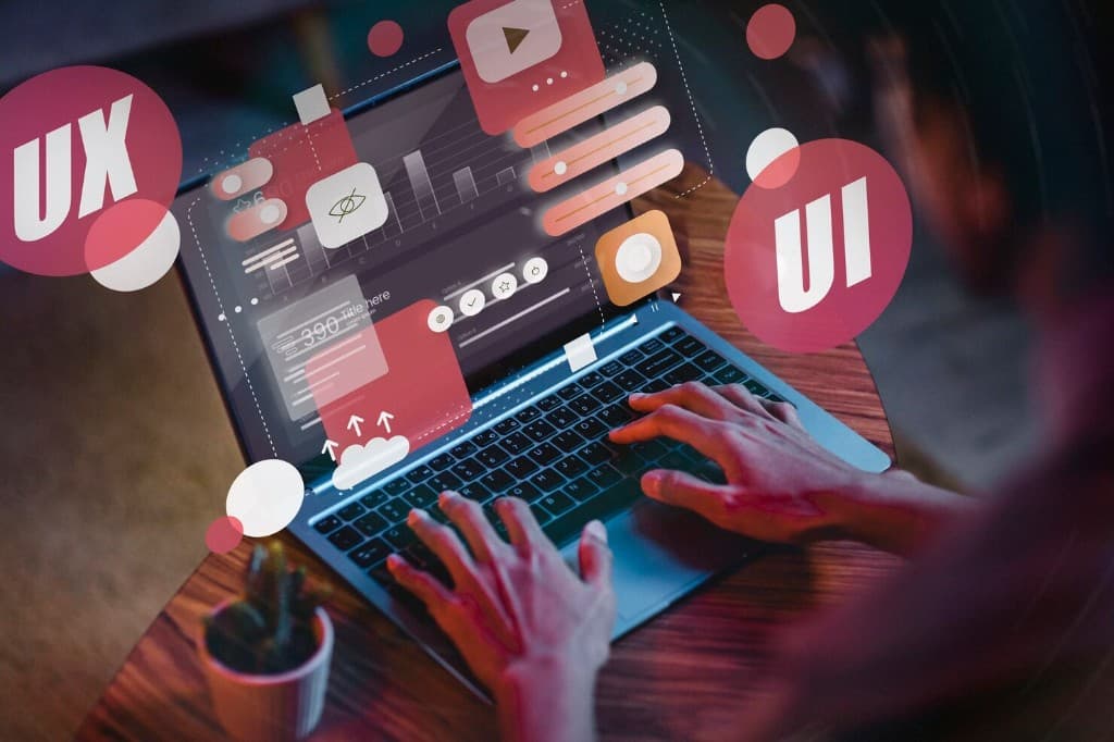Hands working on a laptop surrounded by UX and UI graphics